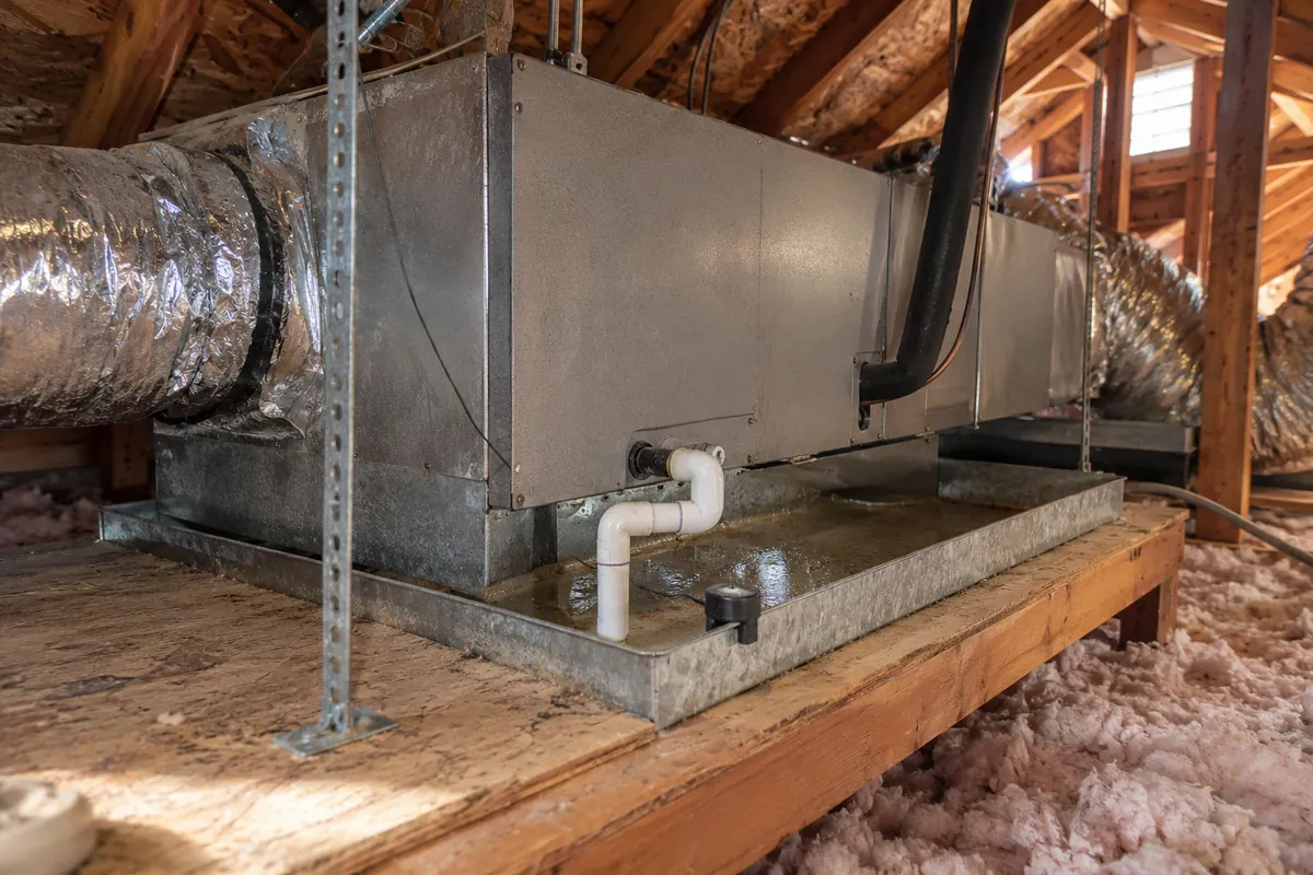 Attic air handler on a wood platform with a drain pan and insulation, attic mold remediation in Denver, CO